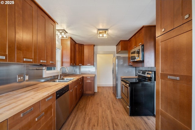 512 Evergreen Dr, Tillamook, OR 97141 - kitchen featuring stainless steel appliances, a sink, brown cabinetry, and light wood-type flooring
