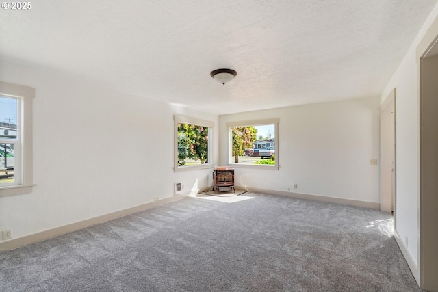 512 Evergreen Dr, Tillamook, OR 97141 - unfurnished room with carpet floors, a wood stove, baseboards, and a textured ceiling