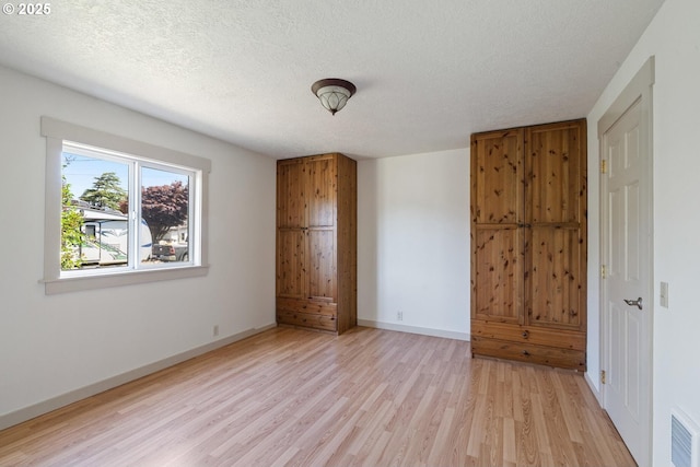 512 Evergreen Dr, Tillamook, OR 97141 - unfurnished bedroom with light wood finished floors, a textured ceiling, and baseboards