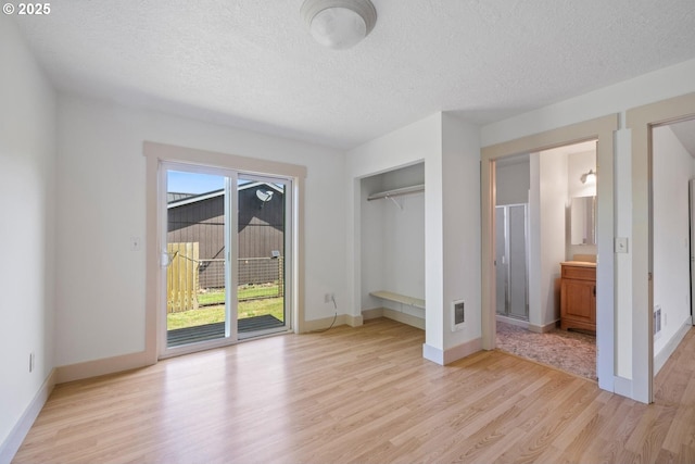 512 Evergreen Dr, Tillamook, OR 97141 - unfurnished bedroom featuring access to outside, light wood-type flooring, a textured ceiling, baseboards, and connected bathroom