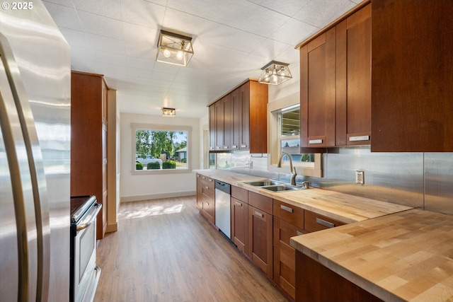 512 Evergreen Dr, Tillamook, OR 97141 - kitchen featuring appliances with stainless steel finishes, wooden counters, a sink, tasteful backsplash, and wood finished floors