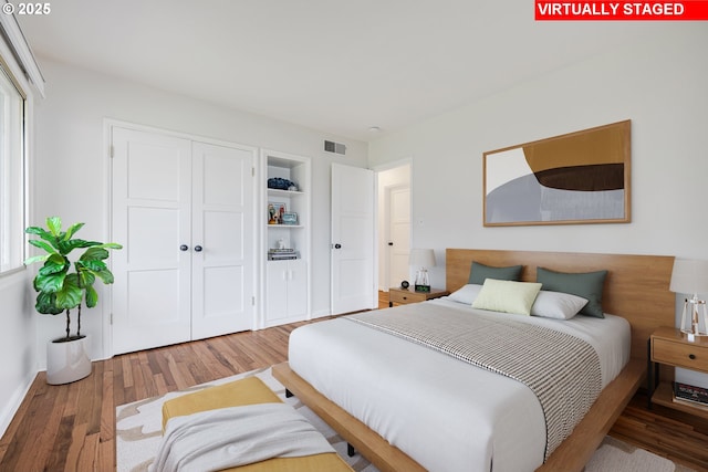 bedroom with a closet, visible vents, and wood finished floors