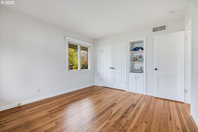 unfurnished bedroom with a closet, visible vents, light wood-style flooring, and baseboards