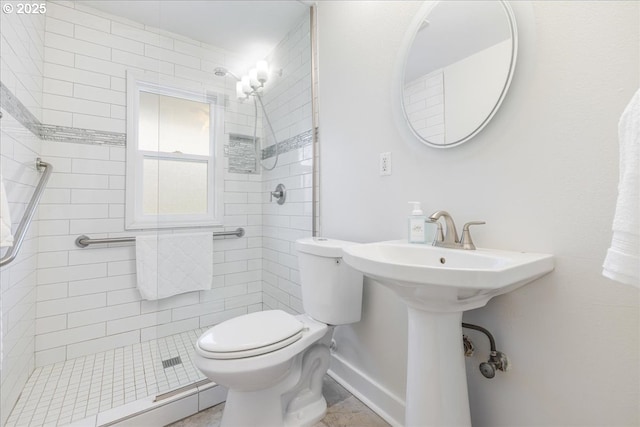 full bath featuring baseboards, tiled shower, and toilet