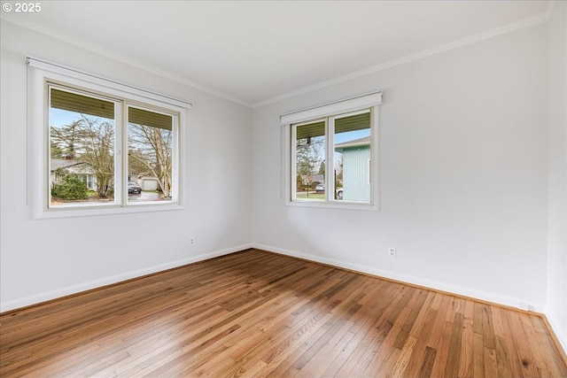 unfurnished room with baseboards, crown molding, and light wood-style floors