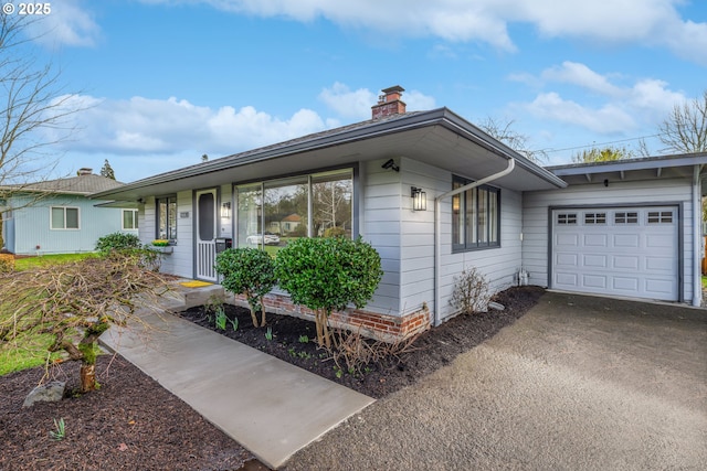 single story home with a garage, driveway, and a chimney