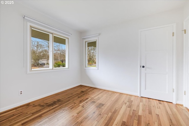 spare room with baseboards and light wood-style floors