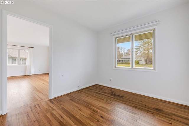 spare room featuring wood-type flooring and baseboards