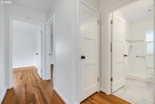 corridor featuring baseboards and wood finished floors