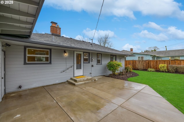 rear view of property with entry steps, fence, a yard, a chimney, and a patio area