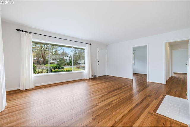 unfurnished living room with visible vents, light wood-style flooring, and baseboards