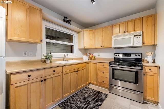 kitchen with light brown cabinets, electric stove, white microwave, and a sink