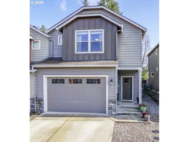 view of front of home with a garage, concrete driveway, board and batten siding, and stone siding