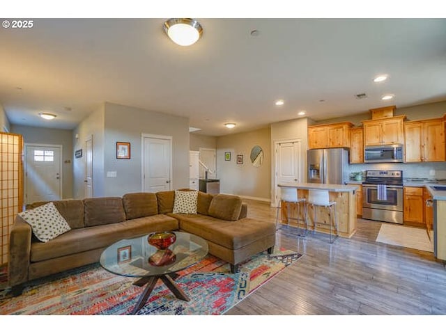 living area featuring light wood finished floors, baseboards, and recessed lighting