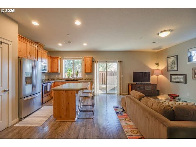 kitchen with open floor plan, stainless steel appliances, dark wood-style flooring, and a center island