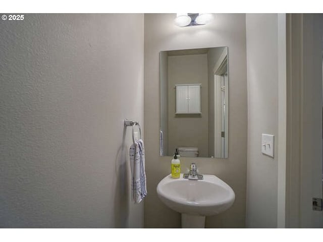 bathroom with a textured wall, a sink, and toilet