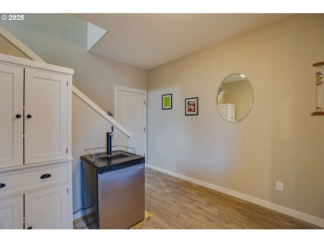 kitchen featuring light wood finished floors, baseboards, and white cabinets