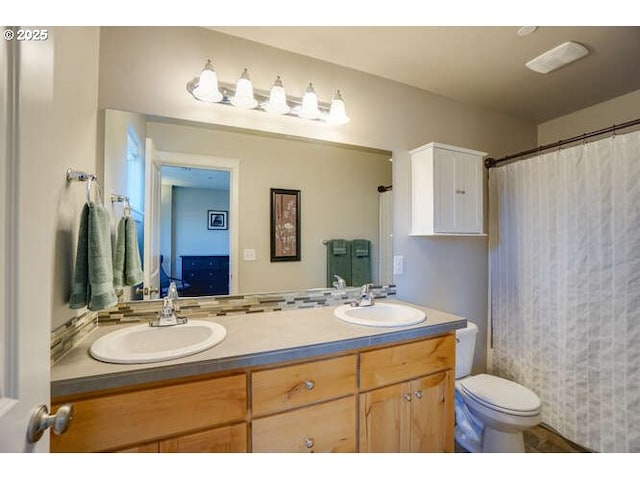 bathroom with double vanity, toilet, and a sink