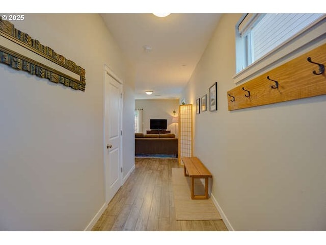 hall with light wood-style floors and baseboards