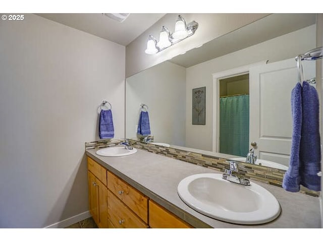 full bathroom with double vanity, a notable chandelier, baseboards, and a sink