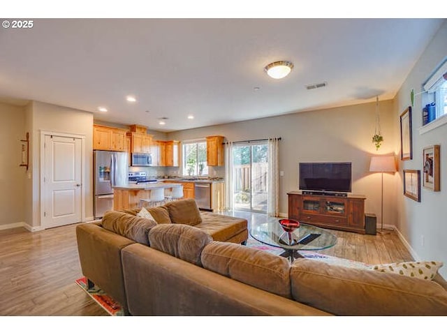 living room with baseboards, light wood-type flooring, visible vents, and recessed lighting