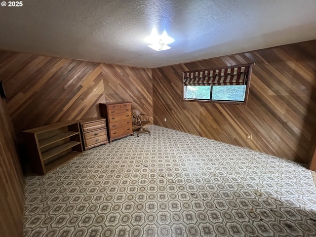 bonus room with wood walls and a textured ceiling