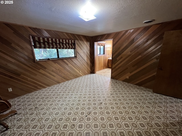 interior space featuring a textured ceiling and wood walls