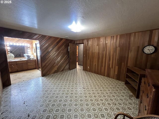 interior space with wood walls, a textured ceiling, and light floors