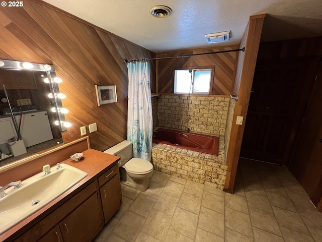 bathroom featuring tiled shower / bath, toilet, a textured ceiling, wooden walls, and vanity