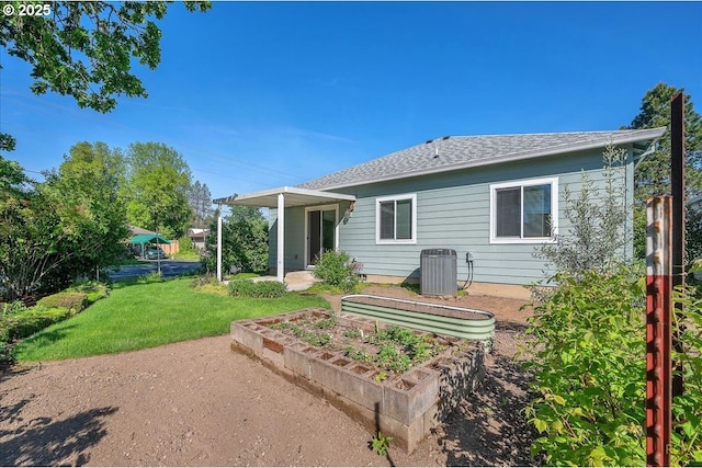 back of property with a lawn, roof with shingles, and cooling unit