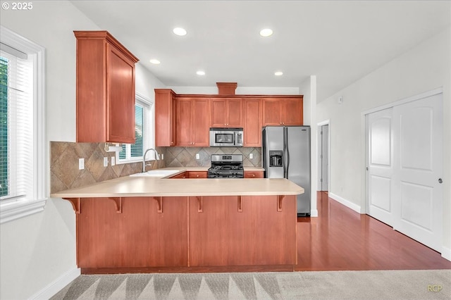 kitchen with appliances with stainless steel finishes, a sink, baseboards, light countertops, and recessed lighting