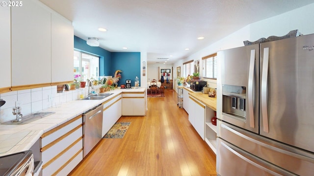 95169 Vista Loop, Gold Beach, OR 97444 - kitchen featuring stainless steel appliances, a sink, light wood-type flooring, white cabinetry, and tile countertops
