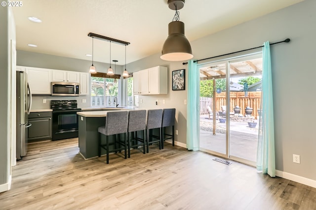 1219 34th Pl, Forest Grove, OR 97116 - kitchen featuring stainless steel appliances, light wood-type flooring, a peninsula, white cabinets, and a kitchen bar