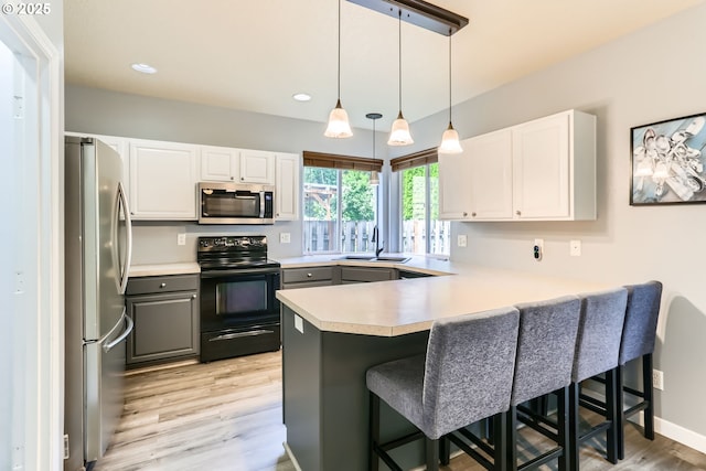1219 34th Pl, Forest Grove, OR 97116 - kitchen featuring stainless steel appliances, a peninsula, light wood finished floors, white cabinets, and a breakfast bar area