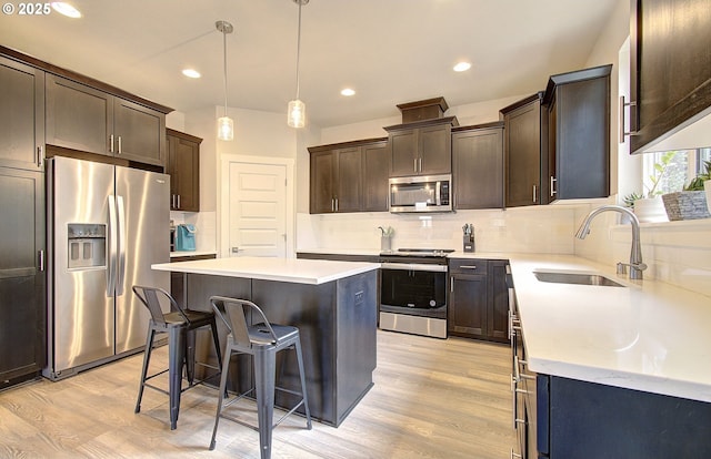 kitchen with a breakfast bar, sink, a center island, light hardwood / wood-style flooring, and appliances with stainless steel finishes