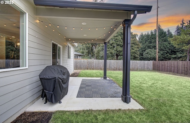 patio terrace at dusk featuring grilling area and a lawn