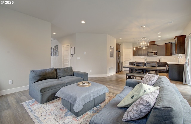 living room featuring a notable chandelier, hardwood / wood-style flooring, and sink