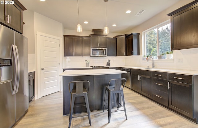 kitchen with sink, light hardwood / wood-style floors, a center island, and appliances with stainless steel finishes