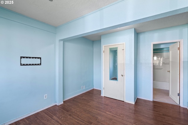 spare room with a textured ceiling, baseboards, and wood finished floors