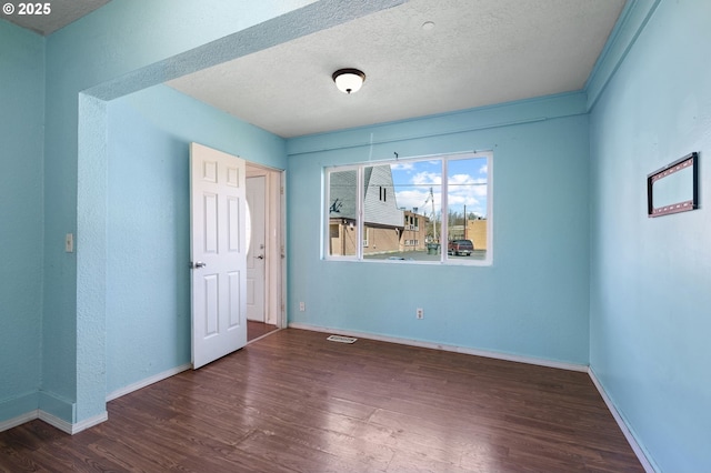 unfurnished room featuring visible vents, baseboards, and wood finished floors