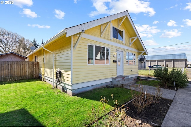 view of front of property featuring entry steps, fence, and a front yard