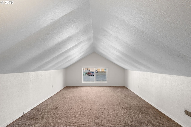 bonus room featuring vaulted ceiling, a textured wall, a textured ceiling, and carpet flooring