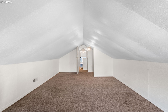 additional living space with carpet floors, vaulted ceiling, and a textured ceiling