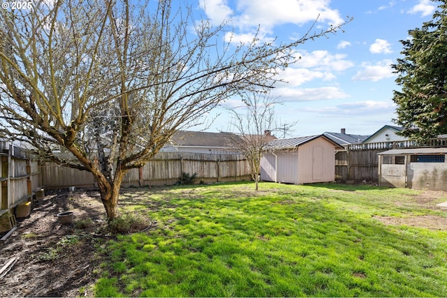 view of yard featuring an outbuilding, a fenced backyard, and a storage unit