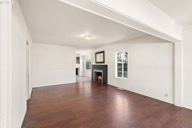 unfurnished living room with a lit fireplace, a textured ceiling, and wood finished floors