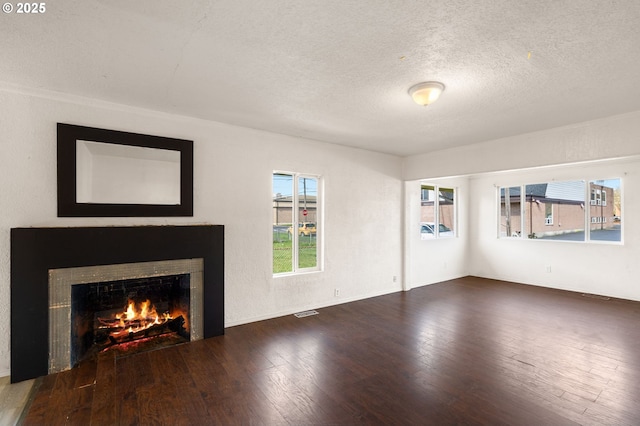 unfurnished living room featuring a textured ceiling, a fireplace, wood finished floors, and visible vents