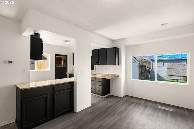 kitchen featuring baseboards, visible vents, dark wood-type flooring, light countertops, and dark cabinetry