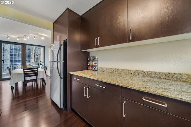 kitchen featuring light stone counters, dark brown cabinetry, stainless steel fridge, and dark hardwood / wood-style floors