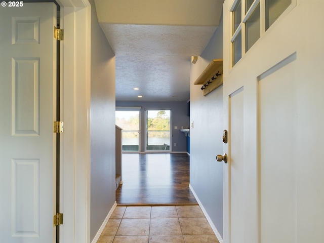 hall with light tile patterned floors and a textured ceiling