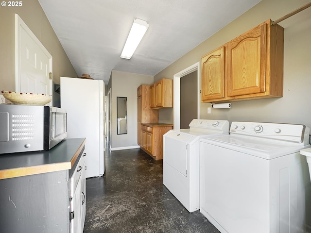 clothes washing area with baseboards, washer and dryer, and cabinet space